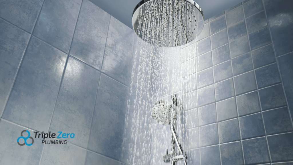 Close-up of a modern showerhead spraying water in a tiled bathroom, with the Triple Zero Plumbing logo in the corner